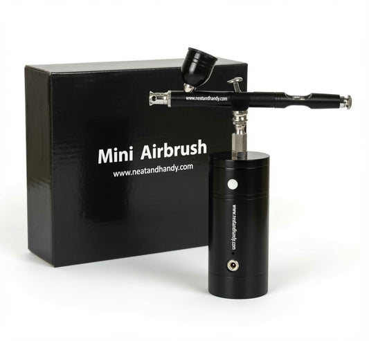 A black mini airbrush tool with a cylindrical body and angled spray arm, shown in front of a black branded box labeled 'Mini Airbrush' and 'www.neatandhandy.